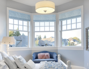 Blue patterned roman shades on large windows in bedroom.