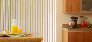 White vertical blinds on a large window in the kitchen.