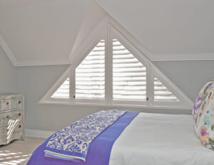 White plantation shutters on a triangular window.